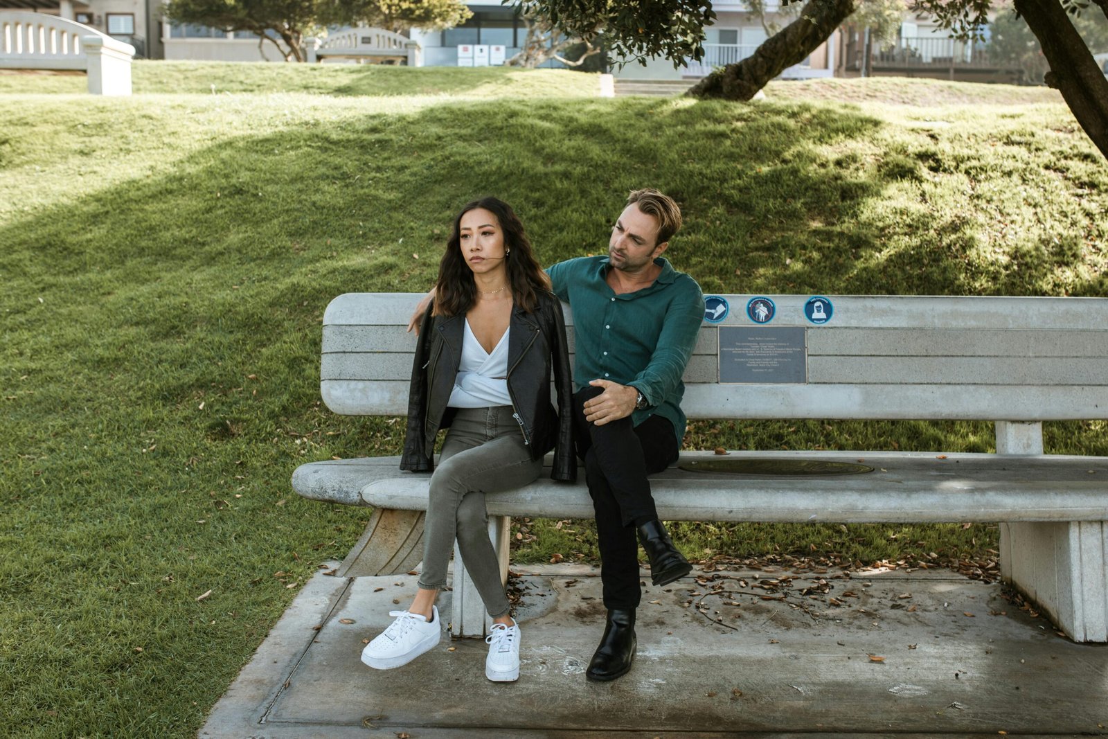 A couple having a serious discussion on a park bench during the day.