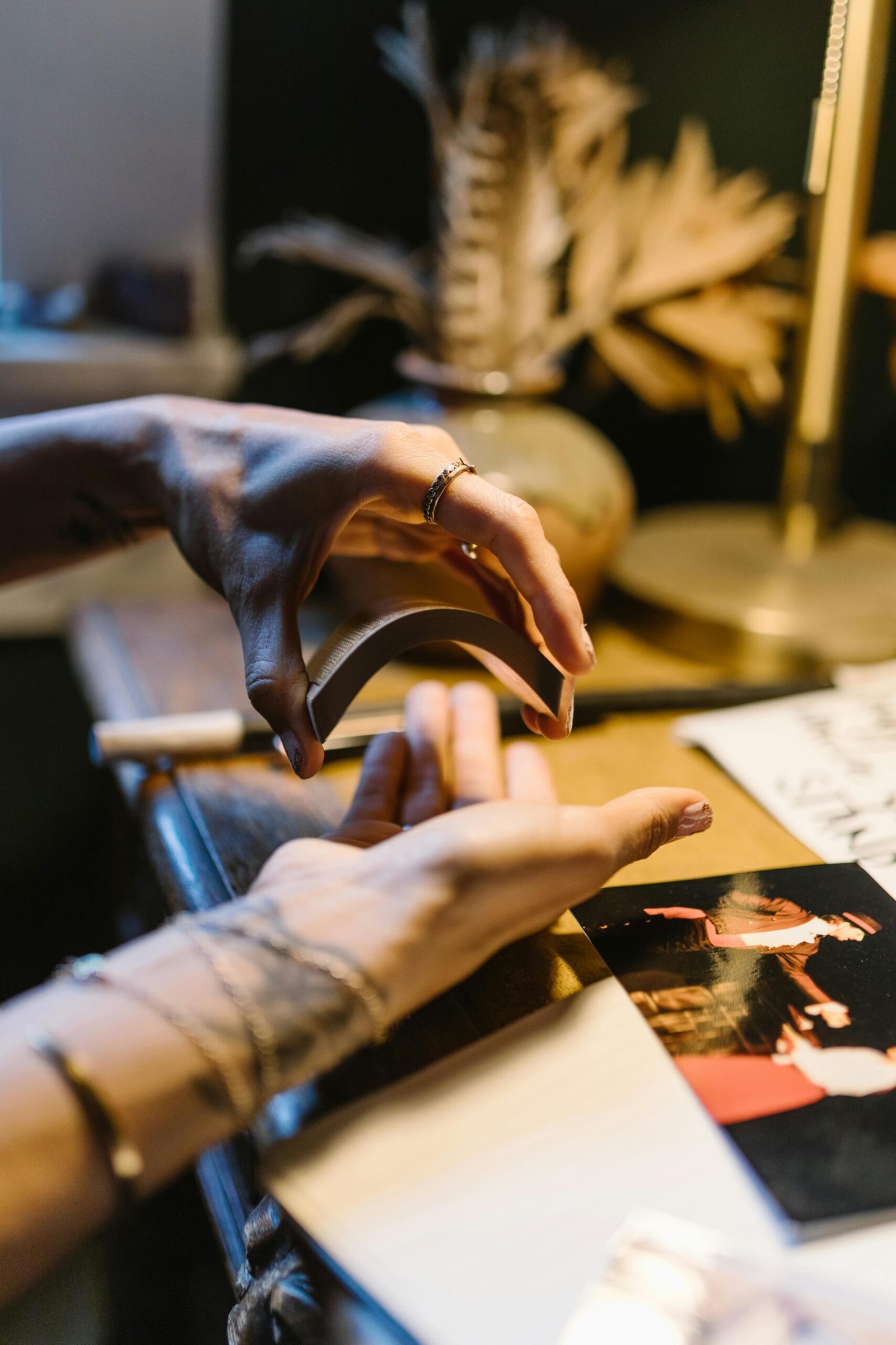 Hands delicately shuffle tarot cards in a mystical setting, suggesting a ritual or reading.
